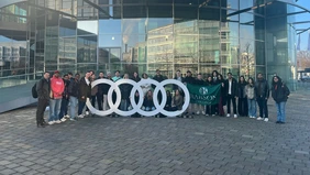 Ein Gruppenfoto vor dem Audi Museum, in der Mitte der Gruppe wird die Flagge des Babson College gezeigt