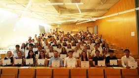 A packed lecture hall filled with people presenting their certificates.