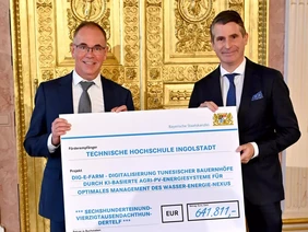 Förderung für ein innovatives Projekt: Professor Wilfried Zörner (l.) nimmt den Scheck von Bayerns Staatsminister für Europaangelegenheiten Eric Beißwenger entgegen (Foto: Bayerische Staatskanzlei). Zwei Männer bei Entgegennahme eines Förderschecks