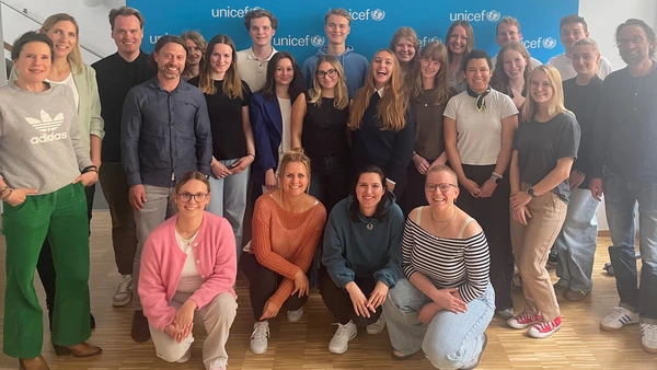 A group photo with a blue Unicef billboard in the background.