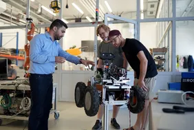 Enblicke in Labore und Vieles mehr gibt es beim THI-Futurelab (Foto: THI). Bild aus dem Futurelab-Labir, wo Herr Kanso zwei Studierenden etwas anhand eines Roboters erklärt