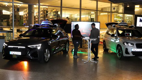 Zwei Forschungsfahrzeuge in der Aula der THI mit Begeleitpersonen