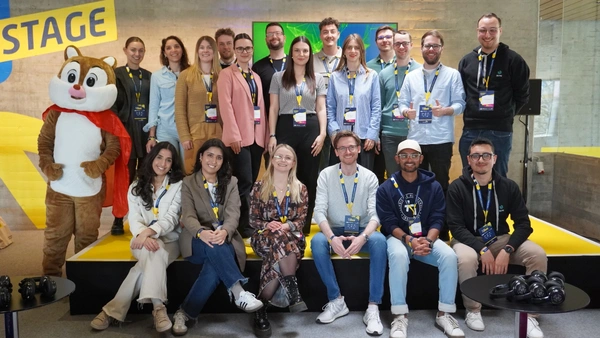 Ein Gruppenfoto mit 19 Personen und einem Maskottchen.