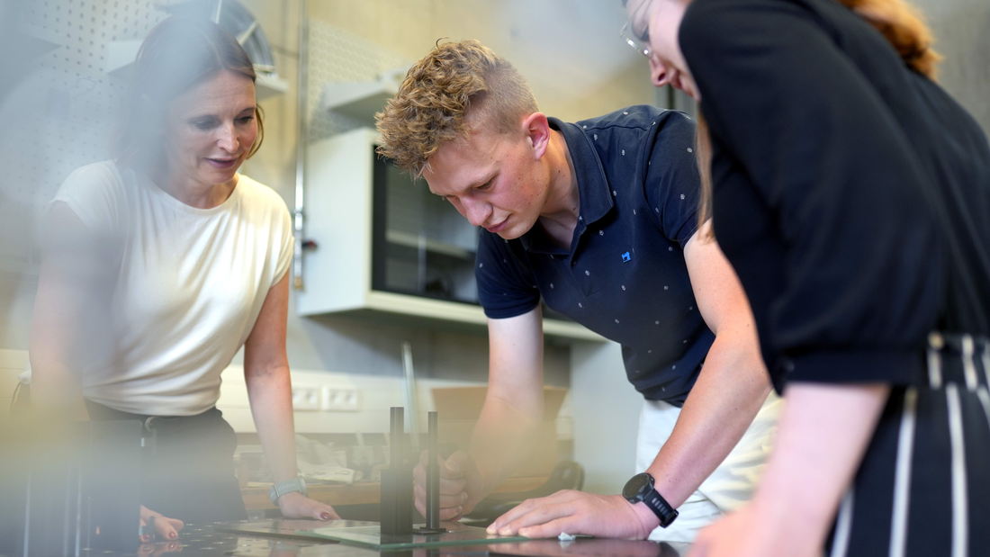 Professorin und 2 Studierende arbeiten in einem Fachraum
