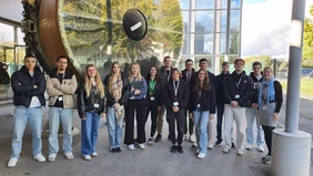 Eine Gruppe Menschen vor einer sehr großen Turbine.