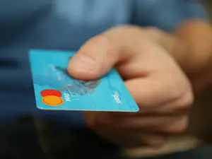 Eine Hand hält eine Kreditkarte zwischen Daumen und Zeigefinge