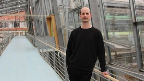 Ein schwarz gekleideter Mann in einem modernen Glasgebäude